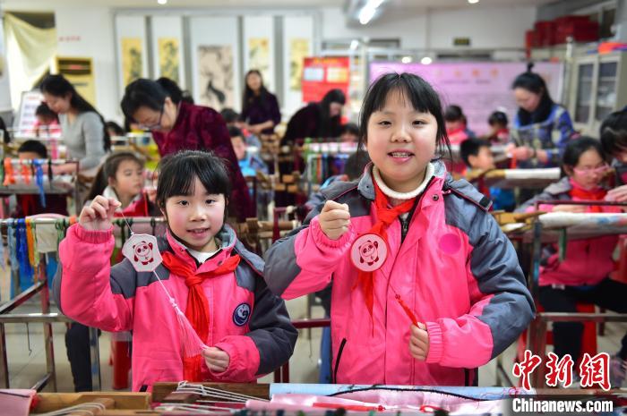 圖為小學(xué)生展示繡制好的2022年北京冬奧會(huì)吉祥物“冰墩墩”形象。　喻云亮 攝