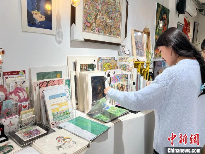 圖為藝術品商店內，顧客挑選插畫作品?！＄婌?攝