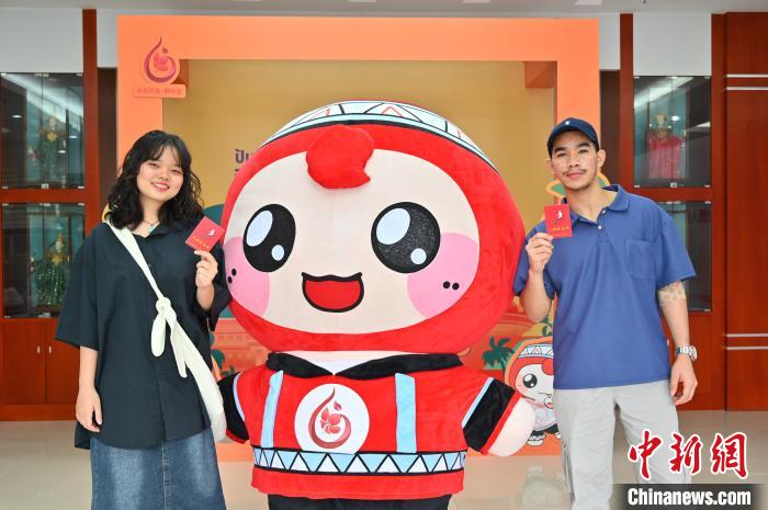 圖為泰國(guó)留學(xué)生手持獻(xiàn)血證與人偶合影。　俞靖 攝