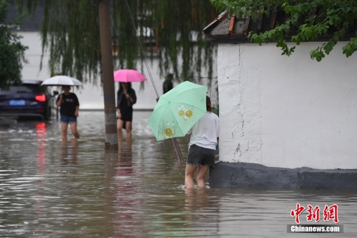 7月31日，市民行走在雨中的北京房山區(qū)瓦窯頭村。北京市氣象臺當(dāng)日10時發(fā)布分區(qū)域暴雨紅色預(yù)警信號。北京市水文總站發(fā)布洪水紅色預(yù)警，預(yù)計當(dāng)日12時至14時，房山區(qū)大石河流域?qū)⒊霈F(xiàn)紅色預(yù)警標(biāo)準(zhǔn)洪水。<a target='_blank' href='/'><p  align=