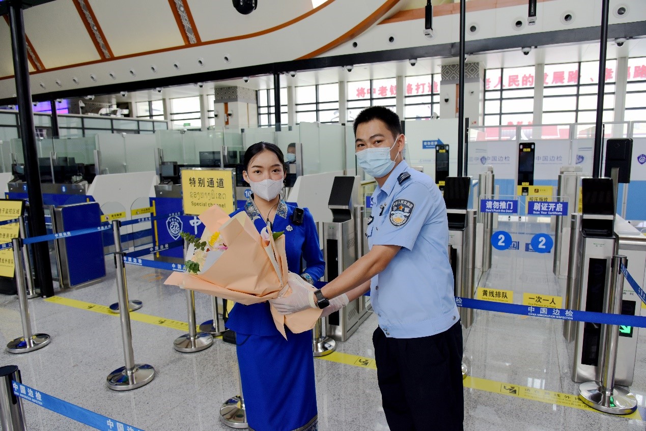 磨憨出入境邊防檢查站民警為中老鐵路第100萬名出入境旅客，D888次國際旅客列車?yán)蠐爰藙?wù)員森達(dá)拉·妮緹婭（Sengdala Nitiya），送上鮮花。黃遠(yuǎn)飛 攝