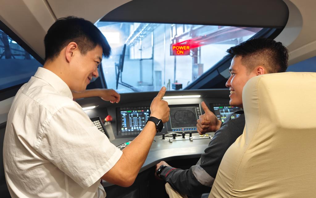 8月25日，在印度尼西亞萬隆的雅萬高鐵德卡魯爾動車所內(nèi)，中國師傅穆振（左）在向印尼火車司機塞蒂亞萬講解動車組出庫前的上電作業(yè)。