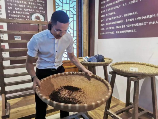 2023“一帶一路”媒體合作論壇聯(lián)合采訪團團員在非遺文化展示館體驗中藥炮制技藝。（本報記者 黃超攝）