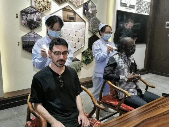 2023“一帶一路”媒體合作論壇聯(lián)合采訪團團員在九牛草展示館體驗艾灸。（本報記者 黃超攝）