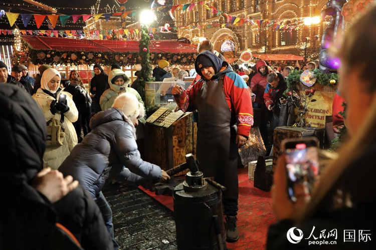 游客在新年集市上體驗制作紀念幣。人民網(wǎng)記者 隋鑫攝