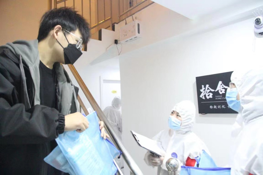 社區(qū)工作人員和志愿者身穿防護(hù)服上門送馬應(yīng)龍大健康防疫包。徐帥攝