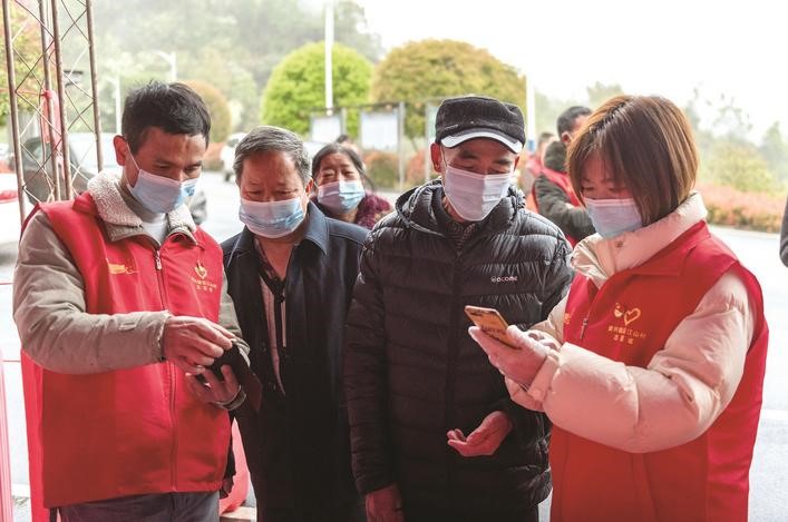 長(zhǎng)沙縣黨員志愿者正在幫助參與核酸檢測(cè)的群眾掃描“場(chǎng)所碼”。劉思源 攝