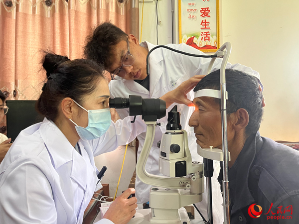 王紅英（左）和團(tuán)隊(duì)成員為達(dá)熱村村民檢查眼睛。人民網(wǎng)記者 杜燕飛攝