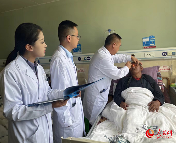 董光明（左三）帶領(lǐng)醫(yī)生對(duì)患者進(jìn)行術(shù)前檢查。人民網(wǎng)記者 杜燕飛攝