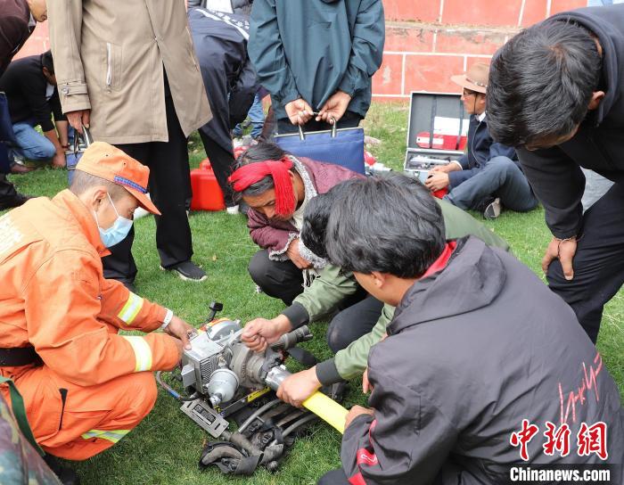 圖為森林消防員為護(hù)林員講解滅火裝備的使用方法?！〔际猩窒乐ш?duì) 供圖