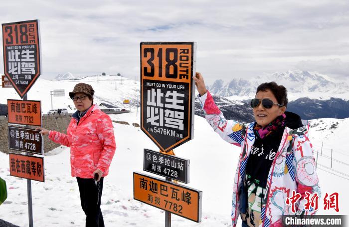 圖為5月14日，西藏林芝色季拉山觀景臺，游客與南迦巴瓦峰合影。　李林 攝