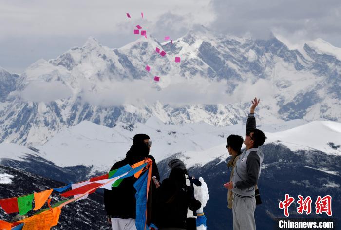 圖為5月14日，游客在西藏林芝色季拉山觀景臺拋灑“隆達”(風馬旗，藏族民眾的一種祈福方式)?！±盍?攝