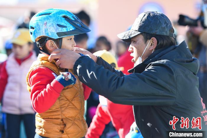 圖為拉薩市實(shí)驗(yàn)幼兒園孩子在教練的幫助下穿戴頭盔?！『闻罾?攝