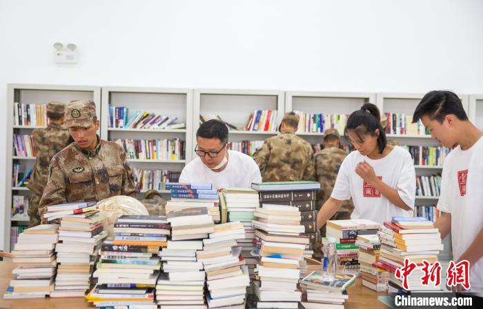 圖為志愿者們和邊防戰(zhàn)士整理圖書。　劉曉東 攝