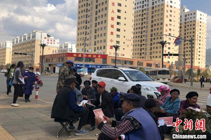 圖為會澤縣城易地扶貧搬遷安置點內(nèi)，老人們聚在廣場上聊天，身后是他們的新家?！】姵?攝
