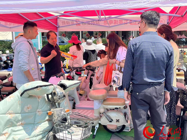 某電動(dòng)自行車(chē)品牌工作人員向消費(fèi)者介紹以舊換新相關(guān)情況。人民網(wǎng)記者 杜燕飛攝