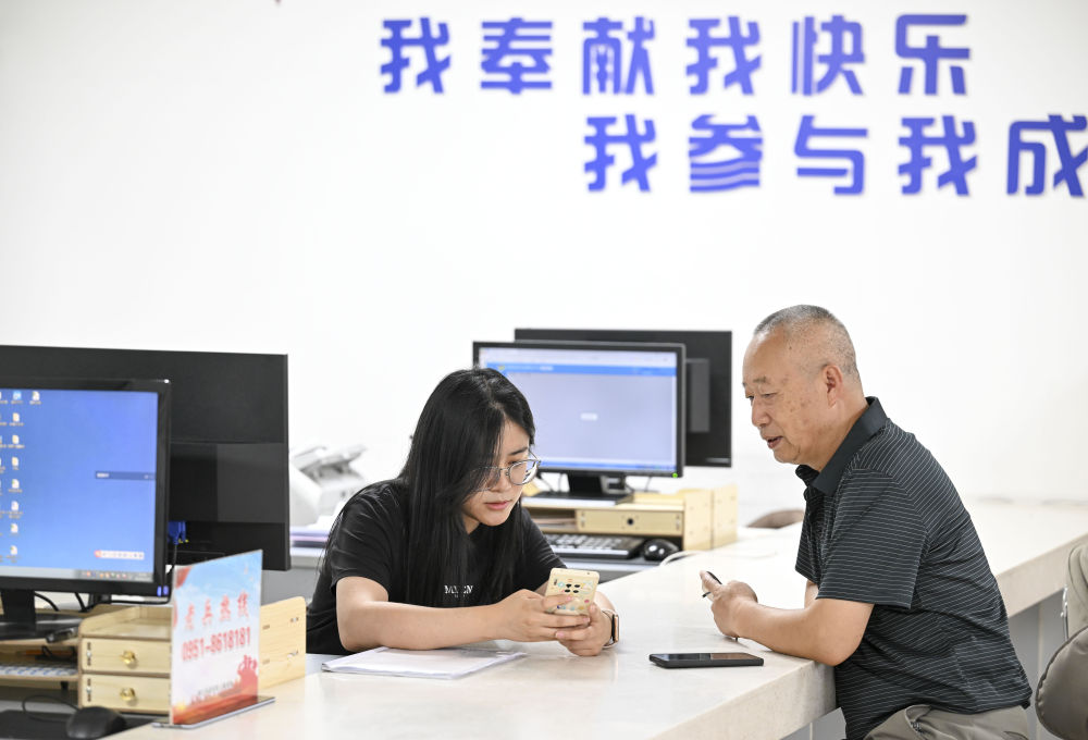 2024年6月20日，在寧夏銀川市金鳳區(qū)長城花園社區(qū)黨群服務中心，工作人員幫助居民辦理業(yè)務。圖片來源 新華社