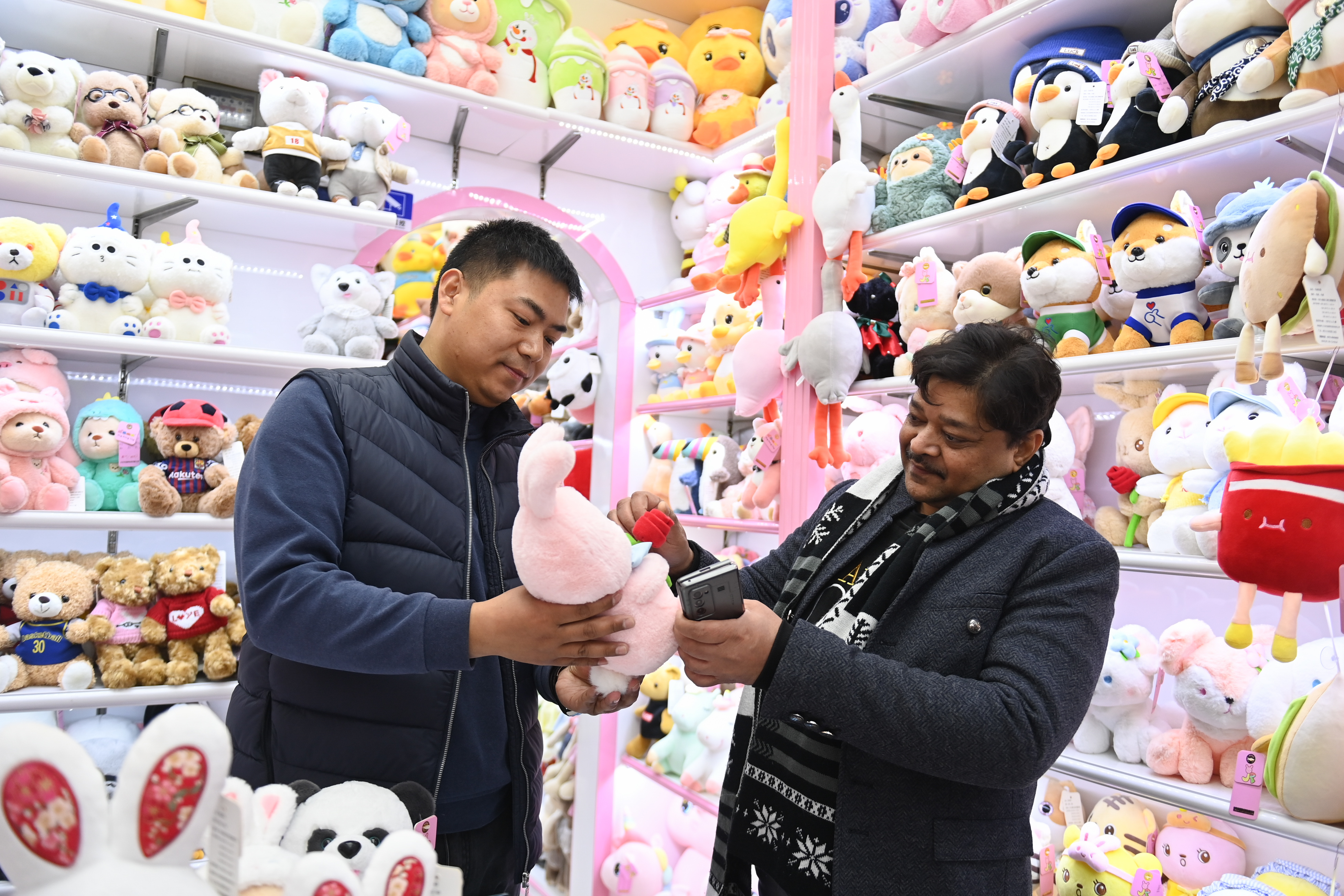 2023年2月2日，來自印度的客商（右）在義烏國際商貿(mào)城的一家玩具店鋪內(nèi)選購。