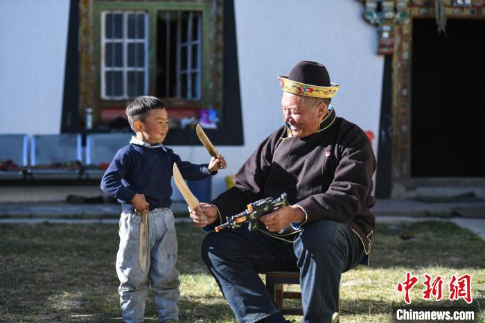 圖為米林縣扎西繞登鄉(xiāng)彩門村64歲的洛桑帶著孫子巴桑在院子的草地上玩耍?！『闻罾?攝