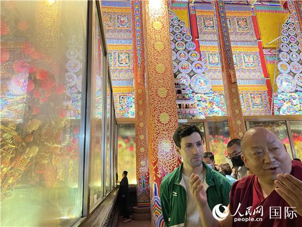 7月25日，省級(jí)非物質(zhì)文化遺產(chǎn)項(xiàng)目塔爾寺酥油花的代表性傳承人朋措堅(jiān)參（右）在塔爾寺酥油花館講解酥油花的制作過程。人民網(wǎng) 謝瑩攝
