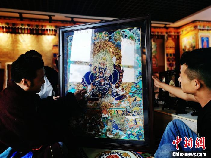 圖為久美尖措(左)與徒弟們展示唐卡作品?！?zhí)砀?攝