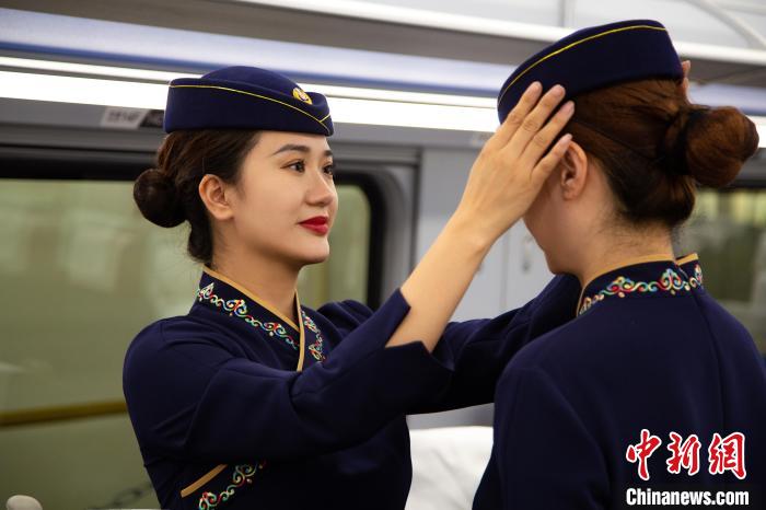 圖為青藏鐵路西格段“復(fù)興號(hào)”動(dòng)車組乘務(wù)員互相整理新制服。　李磊 攝