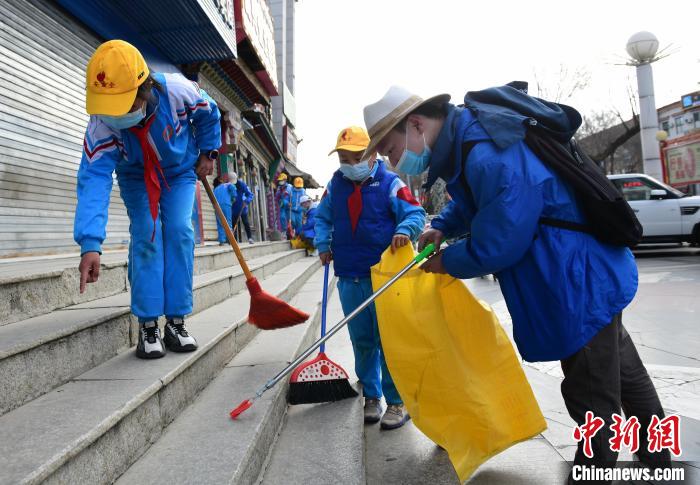 圖為拉薩市小學(xué)生打掃街道?！∝暩聛?lái)松 攝