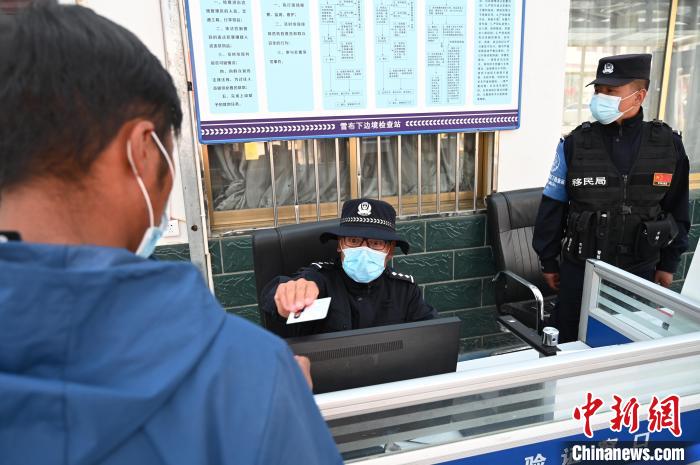 圖為移民管理警察登記完身份信息后將證件歸還給行人?！≮w朗 攝