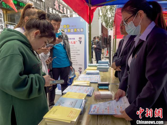 圖為工作人員正在向路過(guò)市民介紹國(guó)家反詐中心軟件的功能?！≈x牧 攝