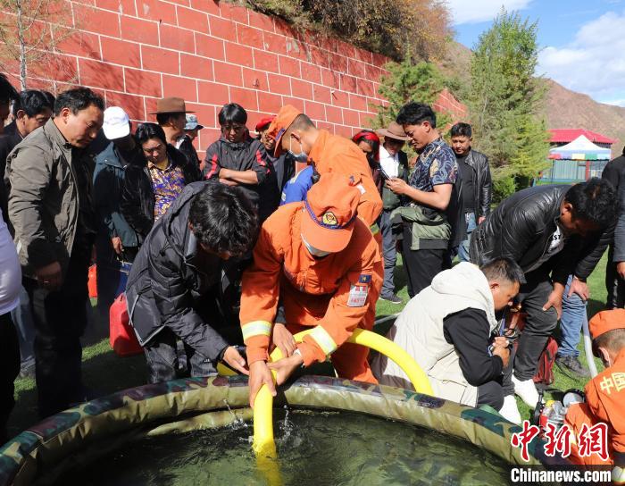 圖為森林消防員為護(hù)林員講解滅火裝備的使用方法?！〔际猩窒乐ш?duì) 供圖
