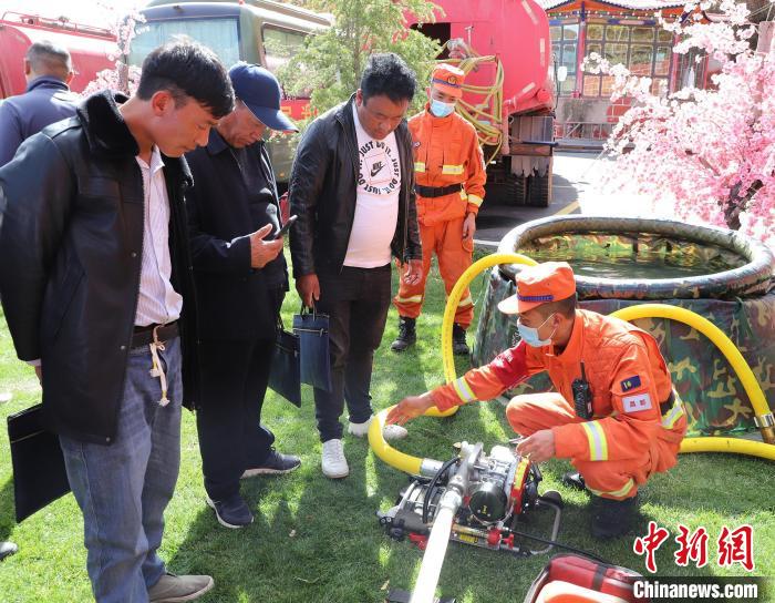 圖為森林消防員為護(hù)林員講解滅火裝備的使用方法?！〔际猩窒乐ш?duì) 供圖