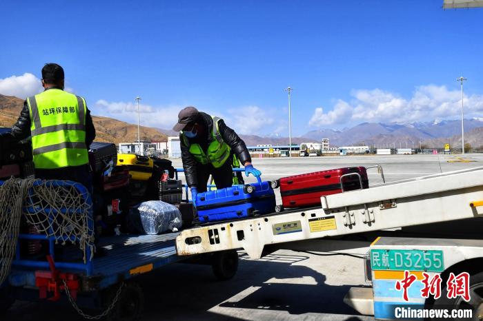 圖為機場工作人員傳送旅客行李箱?！≈芎?攝